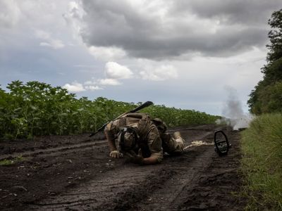 Украинский солдат укрывается, обезвреживая противотанковую мину. Фото: Ed Ram / The Washington Post